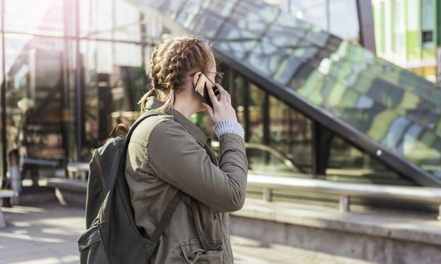 Tjej pratar i mobiltelefon i stadsmiljö.